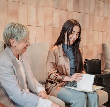 Zwei Frauen sitzen auf einem Sofa und unterhalten sich freundlich. Symbolbild für Beratung. Coachin