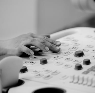 Ultrasonographer with hand on machine keyboard, operating controls.