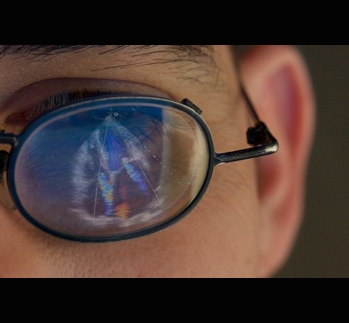 Reflection in eyeglasses of a cardiac ultrasound scan showing valve regurgitation.