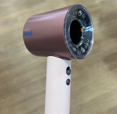 Dyson Supersonic Nural hair dryer in blush pink with clear ring light sensor on wood background.