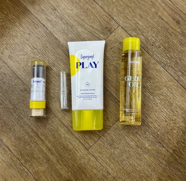 Flat lay of Supergoop! PLAY Lotion, Glow Oil, and SPF powders