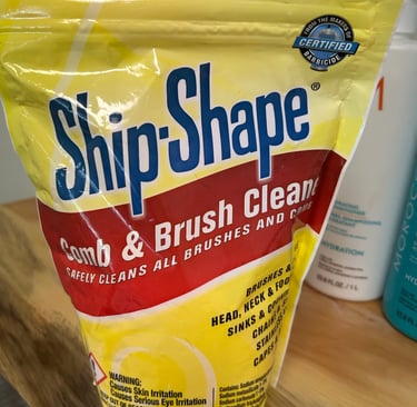 Ship-Shape Comb & Brush Cleaner 2 lb bag on a wooden vanity beside hair products.