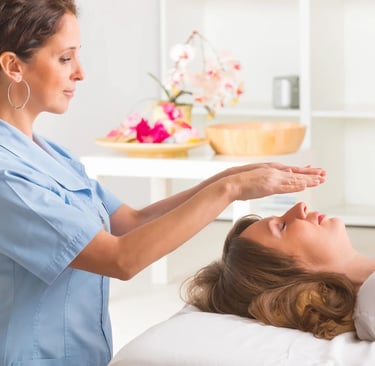 Hovering hands of standing Reiki practitioner over a woman's face who is laying down