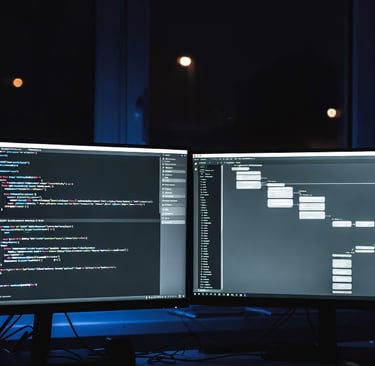 Dual monitor setup for software development showing lines of code and a flow chart.
