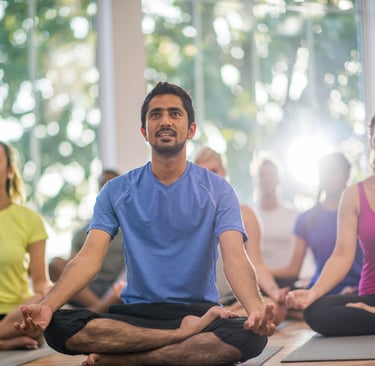 a man and a group of women doing yoga/meditating together