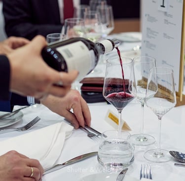 Der Kellner schenkt Rotwein in ein Glas ein.