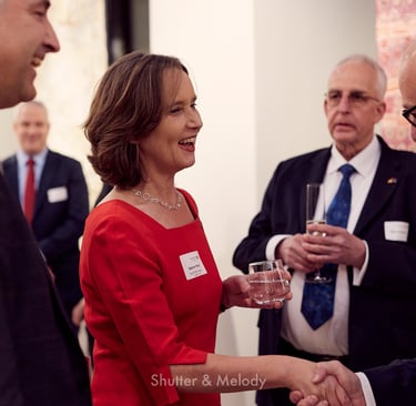 Sabine Pittrof in einem roten Kleid schüttelt einem Gast die Hand.