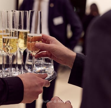 Ein Gast nimmt ein Glas Sekt von einem Tablett in die Hand.