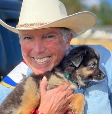 Jen Vrana in a white cowgirl hat holding a puppy