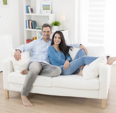 a man and woman sitting on a couch enjoying their air conditioning
