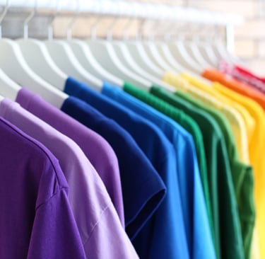 Foto de camisetas colgadas en perchas y ordenadas por el color del arcoiris