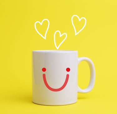 Una taza de café con una cara sonriente en el frontal y en vez de humo salen corazones