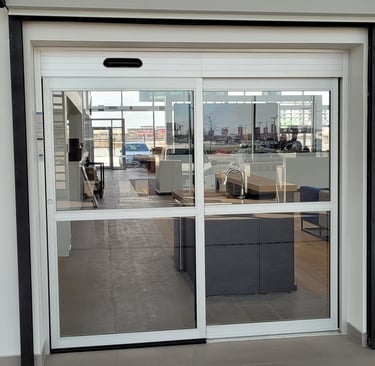 Automatic sliding glass doors with a white frame at a modern commercial building entrance.