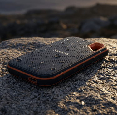 Professional product photography of the SanDisk Extreme Pro V2 SSD on a rugged granite rock. Water d