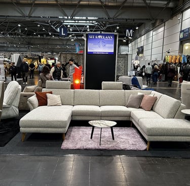 Modern grey sectional sofa and marble coffee table at a furniture trade show exhibition.