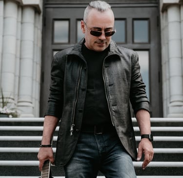a man in a leather jacket and sunglasses holding a guitar