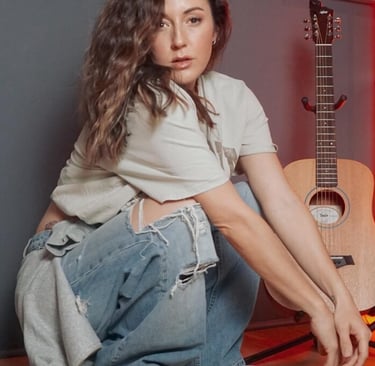 a woman sitting on a wooden floor next to a guitar