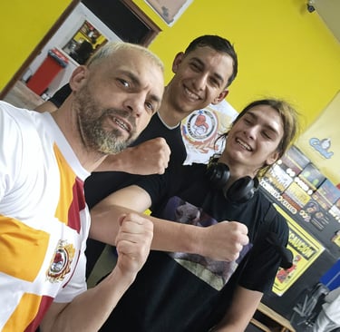 Three smiling athletes posing with fists up inside a local gym with yellow walls.