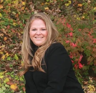 team member from Rise Up Window Coverings smiling outdoors during fall season