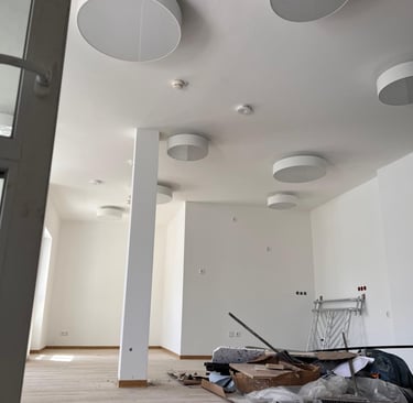 ein großer, weißeer, sanierter Raum mit künstlerischen Trockenbauelementen an der Decke