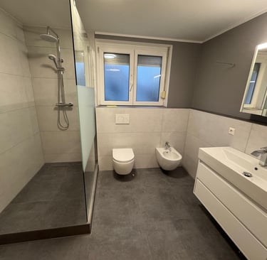ein saniertes Bad. große dusche mit Glaswand, rechts ein WC und ein Bidet sowie ein Waschbecken