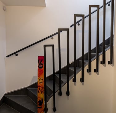 eine frisch sanierte Treppe, gefliest mit schwarzen Fliesen. im vordergrund ein  Treppengitter,