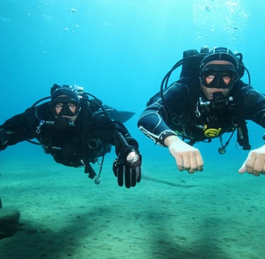 two scuba divers in full bodysuits and diving gear