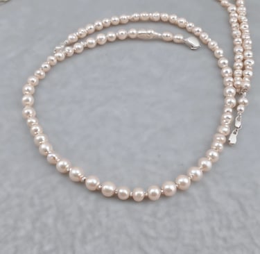 Elegant jewelry pieces featuring intricate designs with pearls and gold accents are displayed against a soft, textured background. The jewelry includes earrings that combine black stones and clusters of pearls with shiny embellishments.