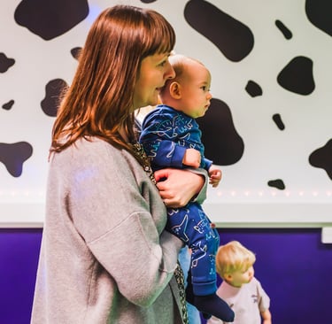 Mum standing, holding her baby in baby moo.