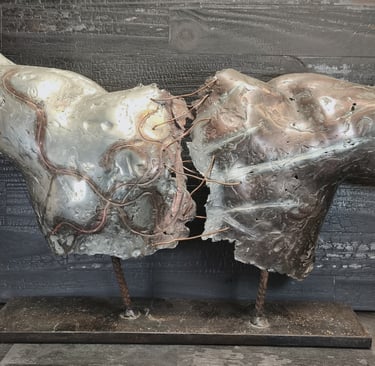 Abstract metal torso sculpture with oxidized copper details on a charred wood background.