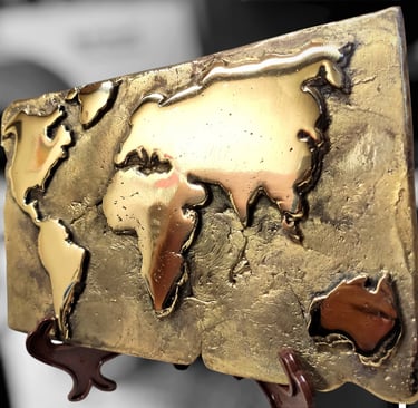 Handcrafted bronze world map plaque on a display stand with a textured metallic finish.
