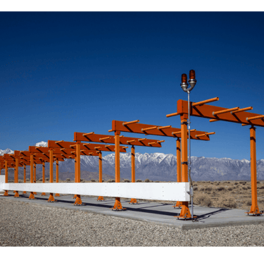 ILS antenna at the end of a runway with mountains behind it.