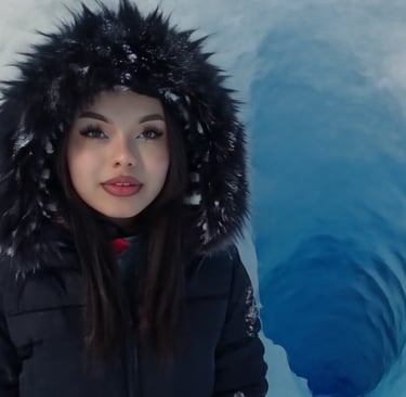 A woman in a black fur hood parka stands in front of a blue ice cave on a winter glacier.