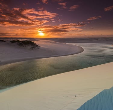 a sunset over a beach with a river running through it