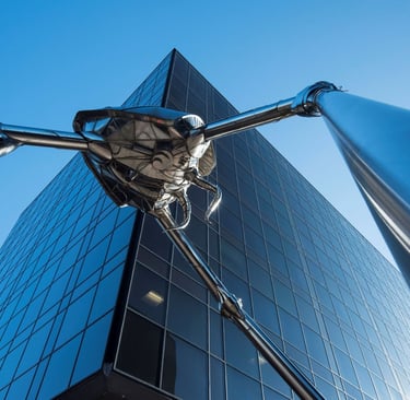 metal statue of futuristic bug in front of office building
