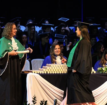 cerimônia de formatura, formando indo em direção ao professor para pegar o canudo de formatura