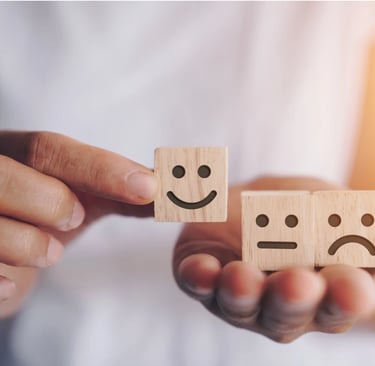 una persona che ha in mano dei cubetti di legno con sopra delle emoticon