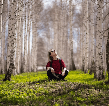 A woman sitting surrounded by a forest.
