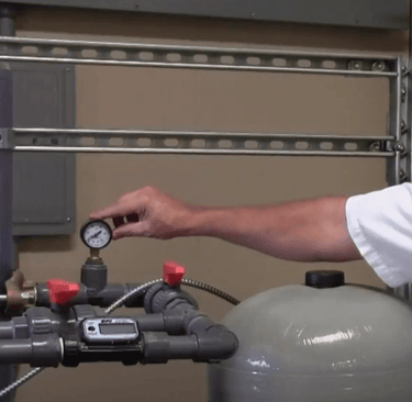 Man pointing to water pressure tank gauge