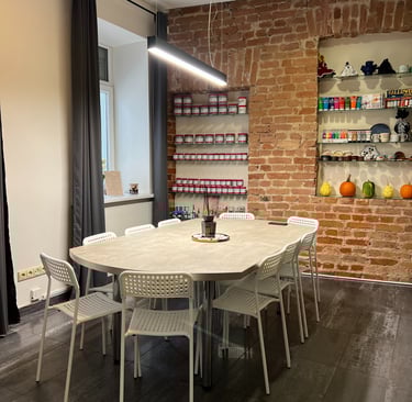 Modern meeting room with white table and chairs against an exposed red brick wall with shelving.