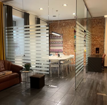 Modern office interior featuring a glass partition wall, meeting room with brick walls, and leather seating.