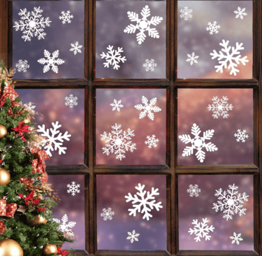 window with christmas tree on the very left with snowflake window stickers on 