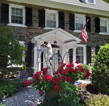 a painter on a ladder painting the front of a house