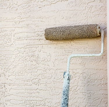 a paint roller painting a stucco wall with a roller roller