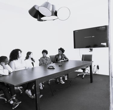 Professional meeting scene where one employee hesitates to speak while others face forward
