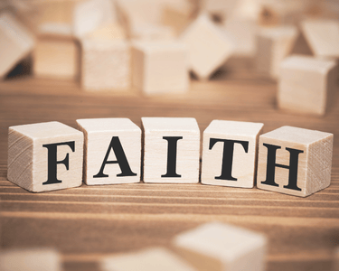 Wooden alphabet blocks spelling the word FAITH on a rustic brown surface.