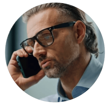 Headshot of a man wearing glasses on a mobile phone.