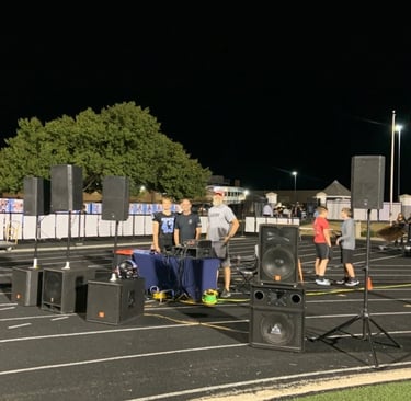 speakers and 5 men standing on a high school track