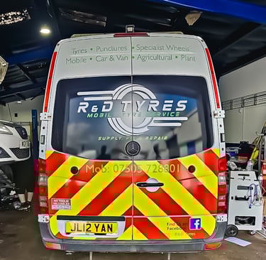 R&D Tyres mobile tyre service van with yellow and red chevrons parked in a garage for repairs.