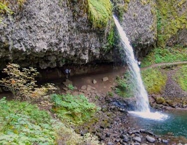 Columbia River Gorge - ponytail falls flows out over a cliff overhang into a blue/green pool